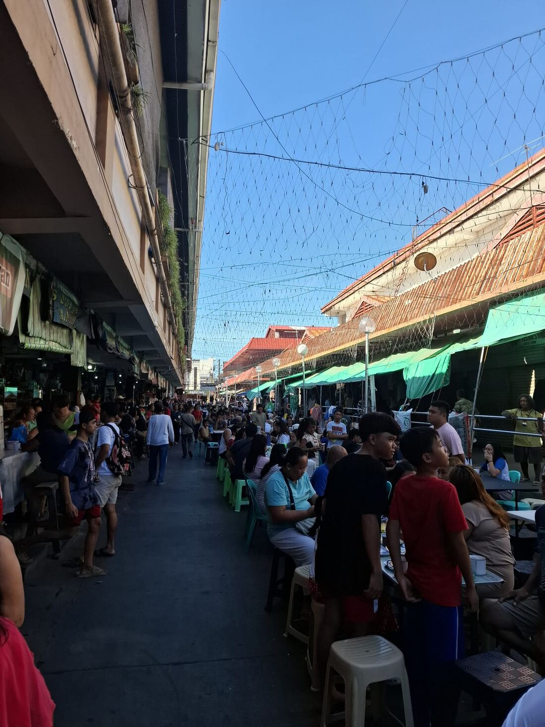 Crowded alley of Dumaguete City Public Market showing rows of vendor stalls and afternoon diners